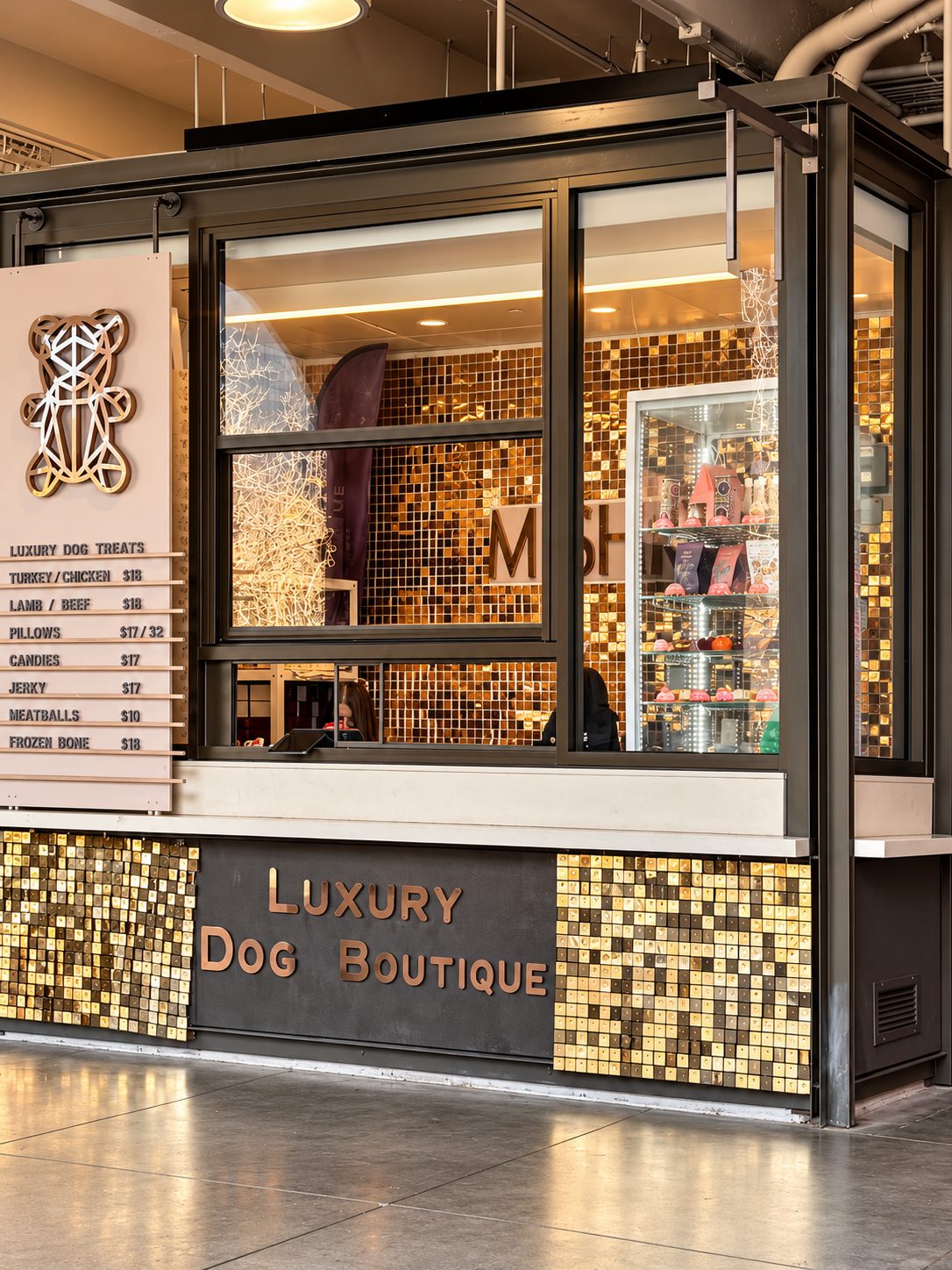 The MISHKA kiosk inside the Ferry Building, with gold mosaic tiles, glass display windows and the bear logo